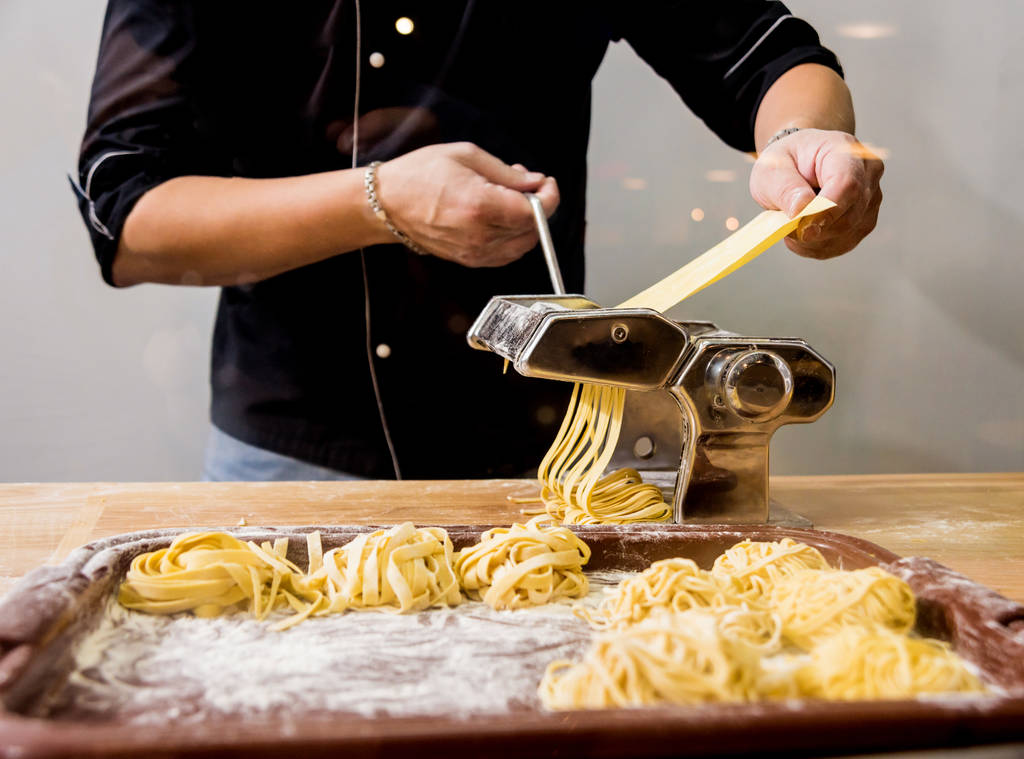 Kokki liikkuvan taikinan kanssa pastaa kone. Pastankeitin. Kotitekoinen italialaistyylinen keittiö. Ravintola
. - Valokuva, kuva