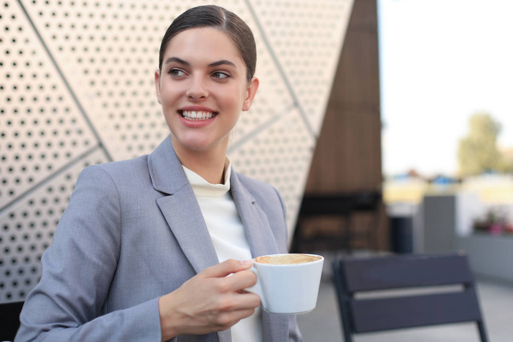 魅力的な笑顔のビジネスマンコーヒーを飲みながらカフェに座っている女性. - 写真・画像