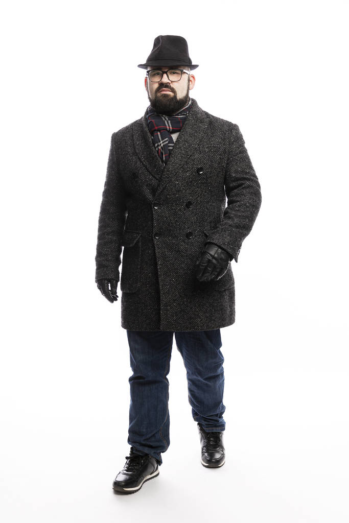 Елегантна людина з бородою в пальто і капелюсі. Повна довжина стоїть на білому тлі
. - Фото, зображення