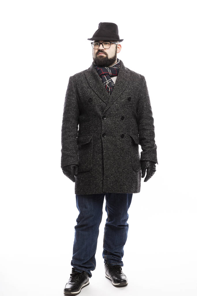 Elegáns férfi szakállal, kabátban és kalapban. Teljes hosszúságú áll fehér háttér.  - Fotó, kép