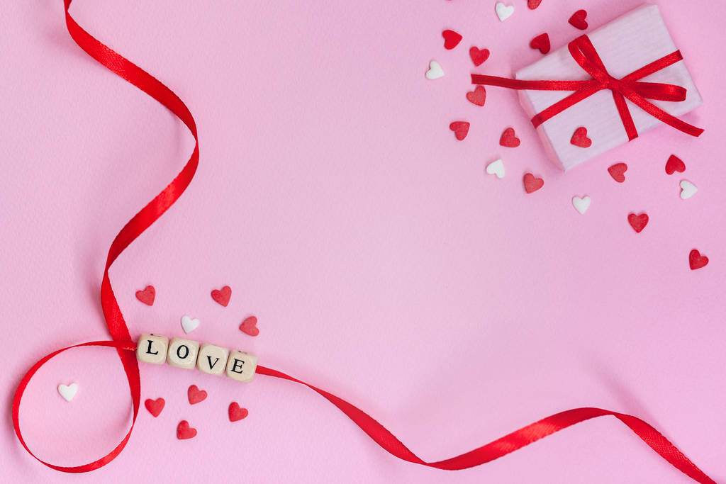 День святого Валентина концептуальное слово "любовь" с белыми и красными сердцами и подарочная коробка на пастельно-розовом фоне. Плоская кладка, вид сверху, копировальное пространство
 - Фото, изображение
