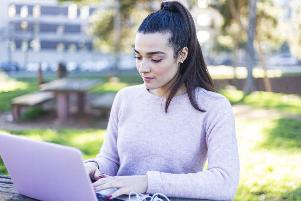 Jovem bela mulher sentada ao ar livre enquanto trabalhava com laptop
 - Foto, Imagem