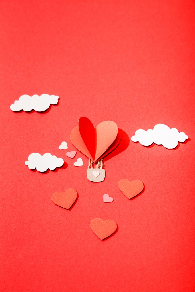 horní pohled na papírové srdce ve tvaru vzduchový balón v mracích na červeném pozadí - Fotografie, Obrázek