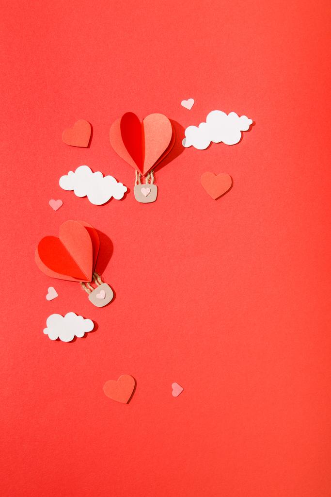top view of paper heart shaped air balloons in clouds on red background - Photo, Image