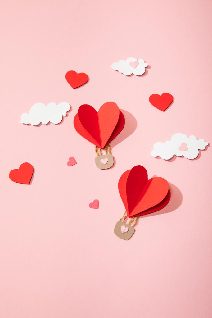 верхний вид бумажных воздушных шаров в форме сердца в облаках на розовом
 - Фото, изображение