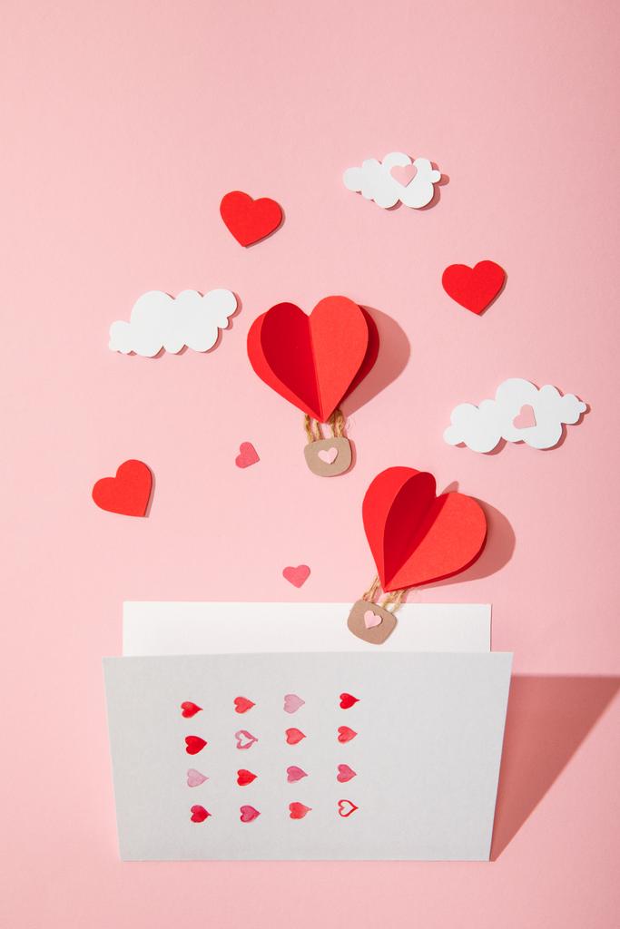 vue du dessus de la carte de vœux avec des coeurs près du papier ballons à air en forme de coeur dans les nuages rose
 - Photo, image