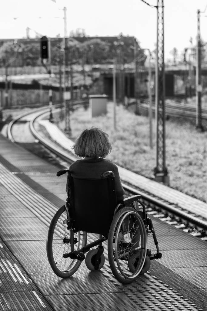 donna seduta su una sedia a rotelle su una piattaforma
  - Foto, immagini