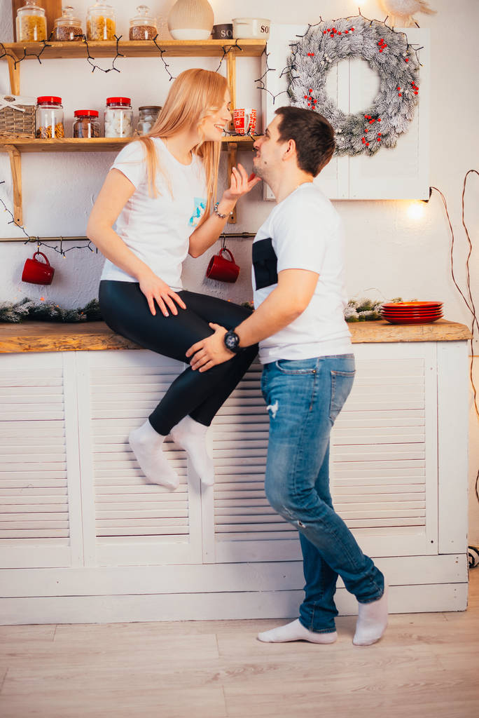 hermosa pareja joven sonriendo el uno al otro en la cocina en Navidad
 - Foto, imagen