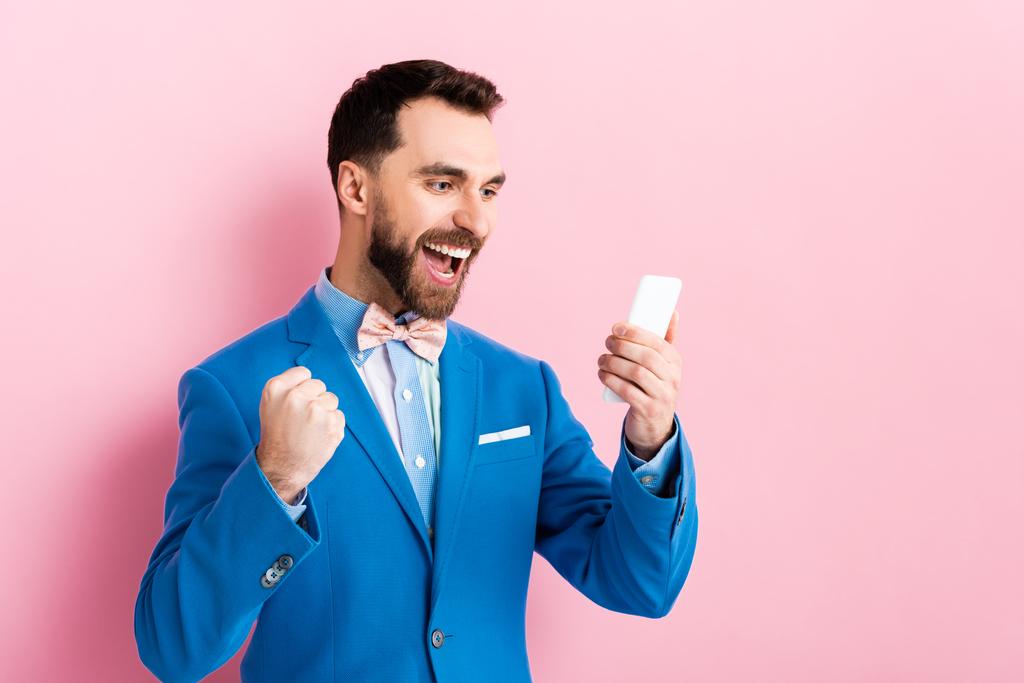 збуджений бородатий бізнесмен тримає смартфон на рожевому
  - Фото, зображення