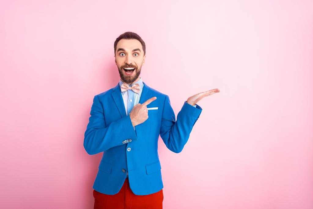 izgatott férfi öltönyben mutogatott ujjal rózsaszín  - Fotó, kép