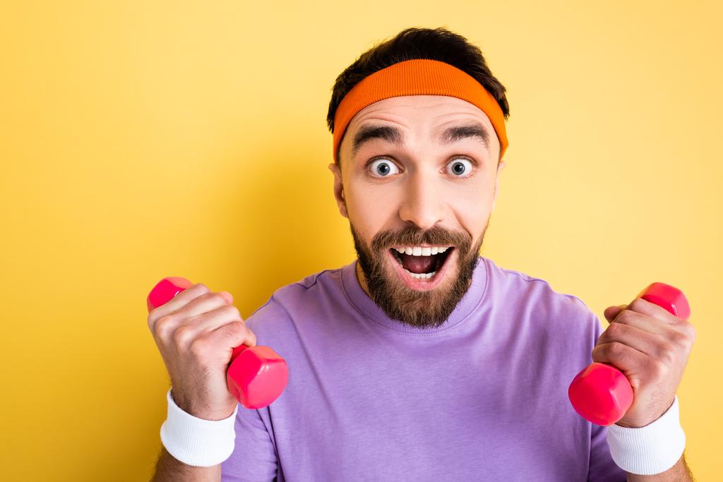 deportista emocionado levantamiento de pesas pequeñas mancuernas de color rosa en amarillo
 - Foto, Imagen
