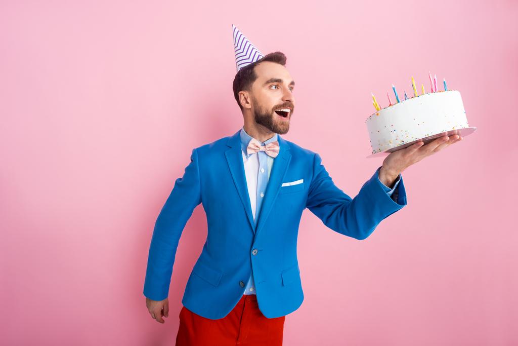 positive businessman in suit looking at birthday cake on pink  - Photo, Image