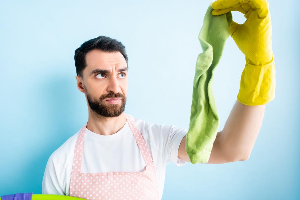 walgelijke man met baard houden vuile sok op blauw  - Foto, afbeelding