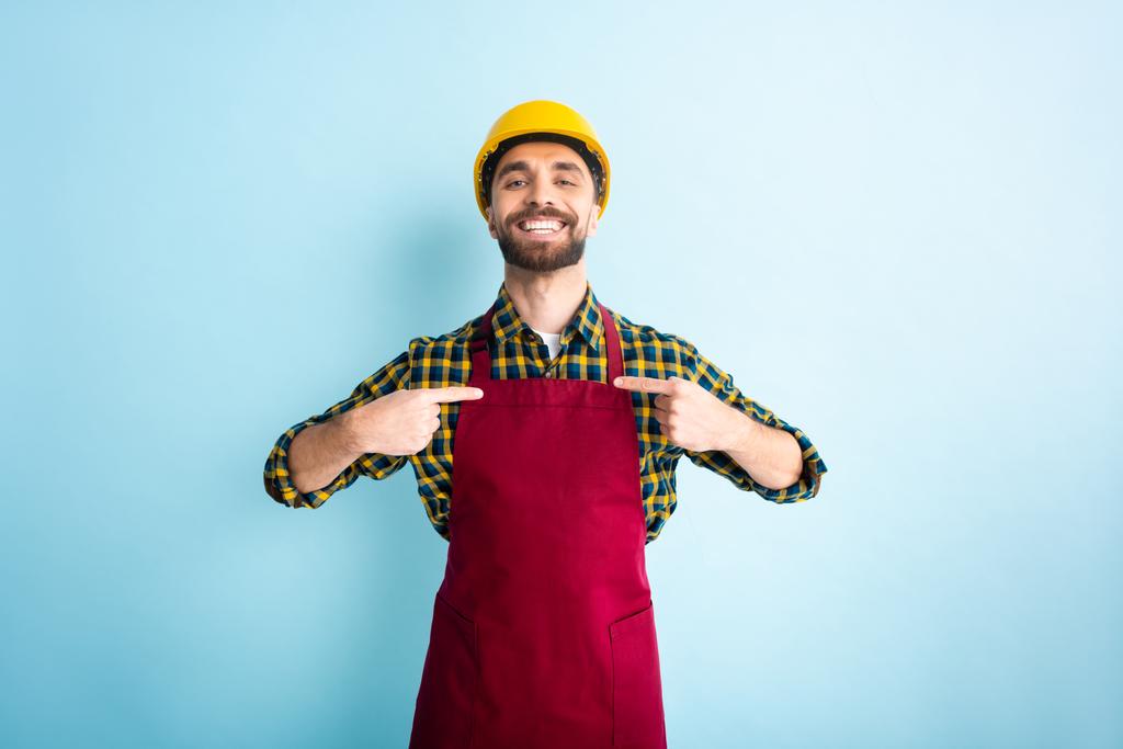 Χαρούμενος εργάτης που δείχνει με τα δάχτυλα στο μπλε  - Φωτογραφία, εικόνα