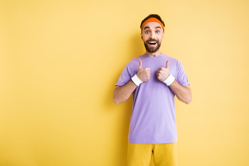 щасливий бородатий спортсмен показує великі пальці вгору на жовтому
 - Фото, зображення