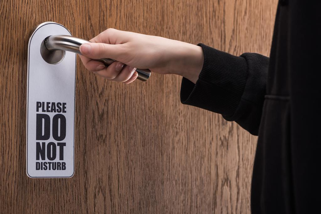 vista recortada de la mujer sosteniendo la manija de la puerta con por favor no molestar signo
  - Foto, Imagen