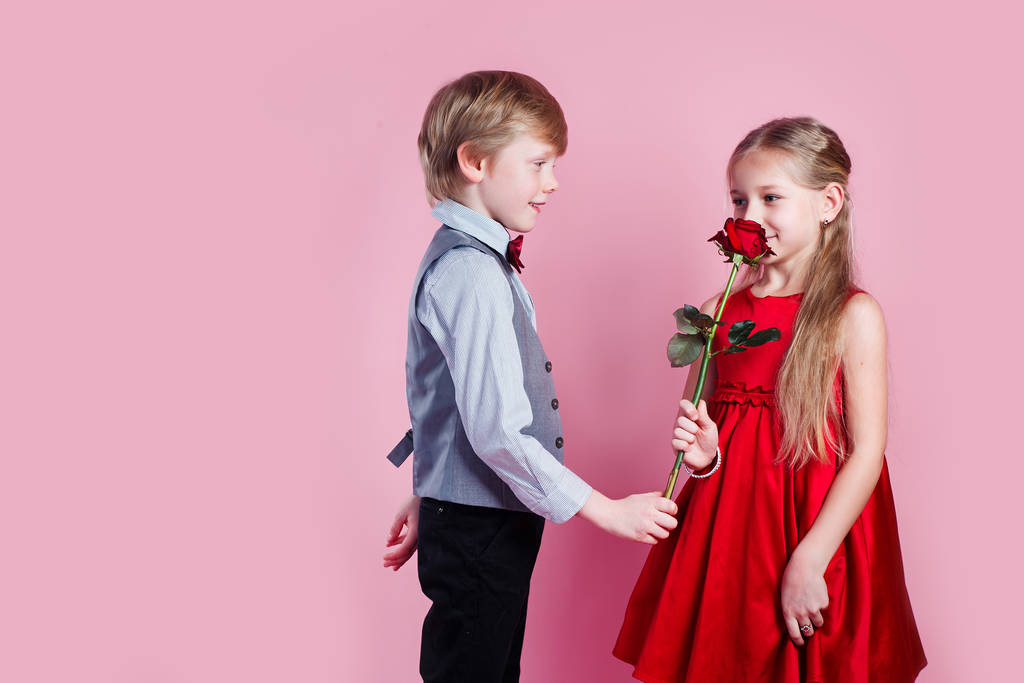Αγόρι στην αγάπη δίνει χαριτωμένο κορίτσι κόκκινο τριαντάφυλλο, Ημέρα του Αγίου Βαλεντίνου έκπληξη - Φωτογραφία, εικόνα
