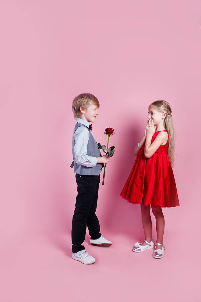 可愛いです女の子の赤いバラを与える愛の小さな男の子,バレンタインデー - 写真・画像