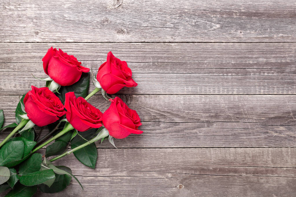 Fiori di rose rosse su tavolo di legno grigio. Biglietto d'auguri di San Valentino. Vista dall'alto. Copia spazio
 - Foto, immagini