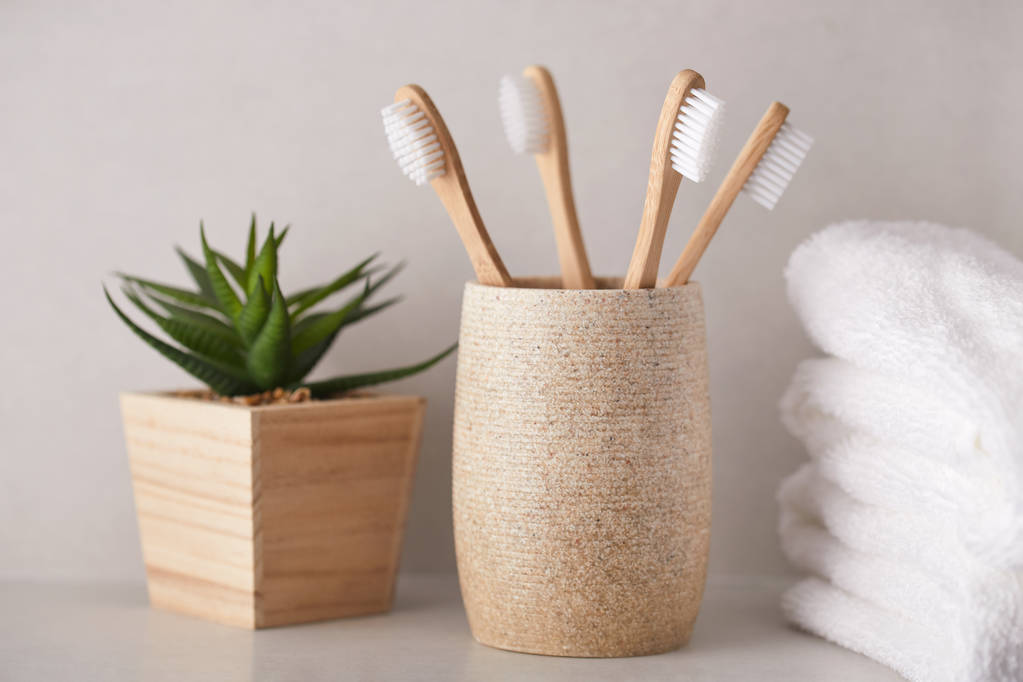 Escovas de dentes de bambu orgânico com toalhas brancas no banheiro
 - Foto, Imagem
