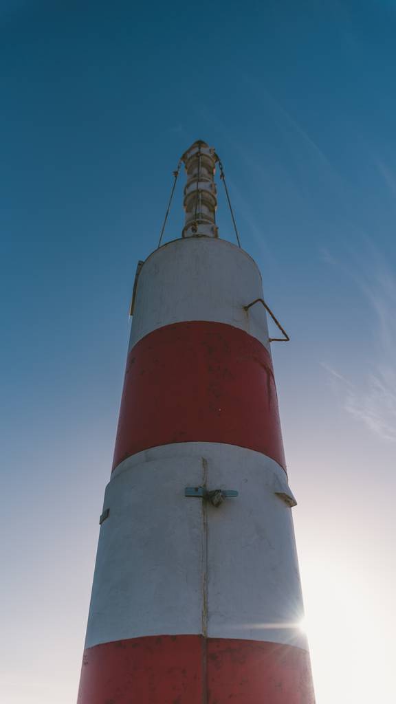 Un tiro vertical de bajo ángulo de un faro rojo y blanco bajo el hermoso cielo brillante
 - Foto, imagen