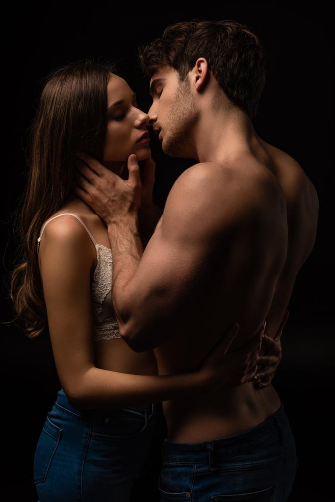 sexy joven pareja besándose con cerrado ojos aislado en negro
 - Foto, Imagen