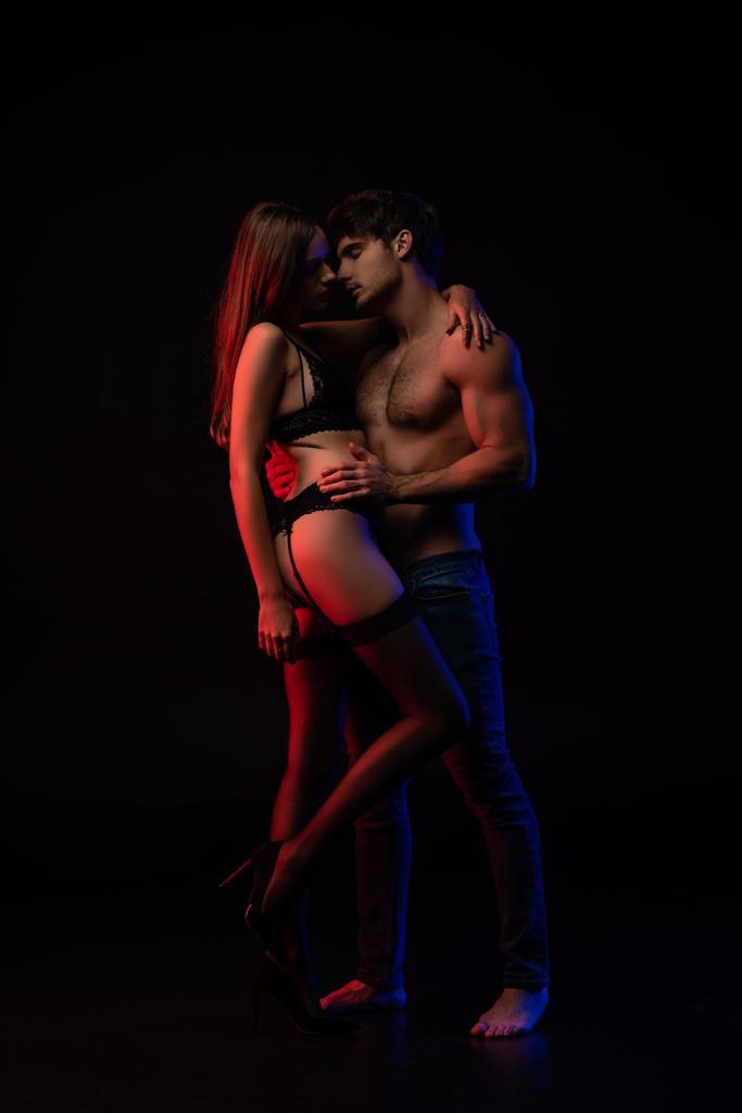 裸のセクシー若いカップルキスと抱擁で赤の光で隔離された黒 - 写真・画像