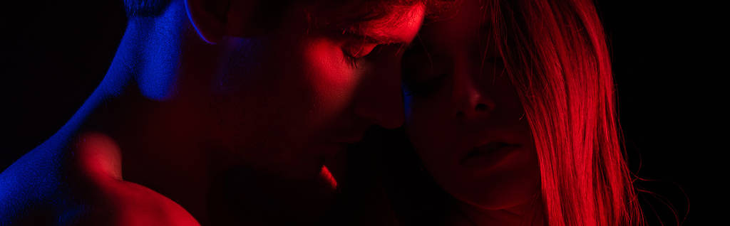 despiu sexy jovem casal beijando em luz vermelha isolado no preto, tiro panorâmico
 - Foto, Imagem