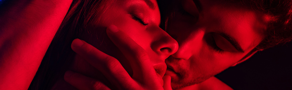 Tutkulu genç çiftin kırmızı ışıkta öpüşmesini yakın çekim, panoramik çekim - Fotoğraf, Görsel