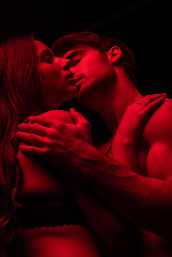 παθιασμένο σέξι νεαρό ζευγάρι φιλιά στο κόκκινο φως απομονώνονται σε μαύρο - Φωτογραφία, εικόνα