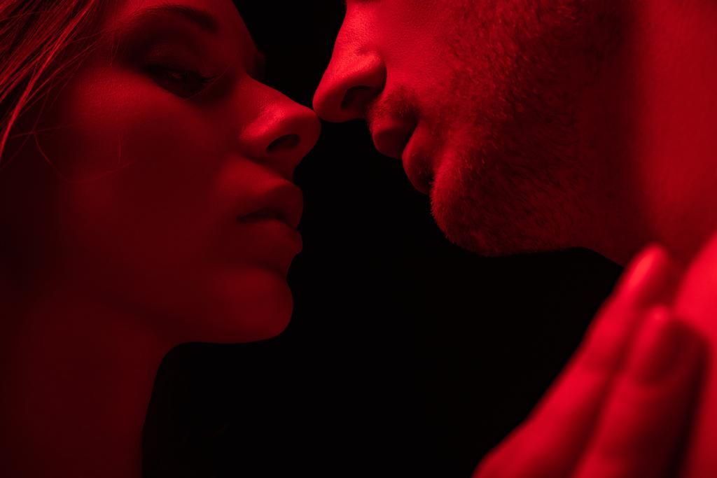 szenvedélyes szexi fiatal pár csók piros fény elszigetelt fekete - Fotó, kép