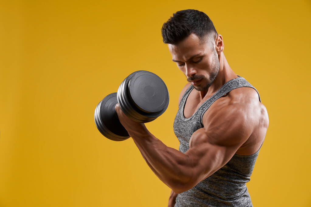Svalnatý mladý muž pumpující biceps - Fotografie, Obrázek