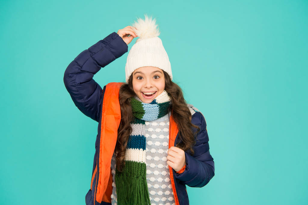 Wat een hoed. Gelukkig kind draagt warme hoed. Klein meisje glimlach in pompom hoed. Fashion accessoire voor de winter. Mode en stijl. Warme en stijlvolle muts voor koud weer - Foto, afbeelding