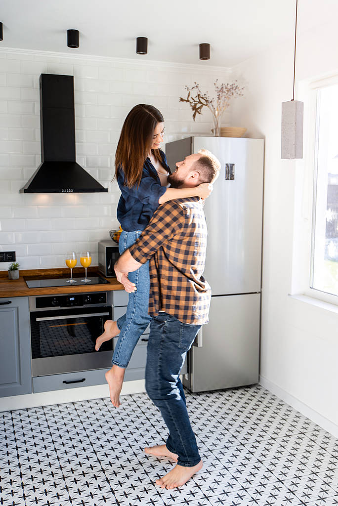 Um cara com uma garota em camisas casuais xadrez na cozinha
 - Foto, Imagem