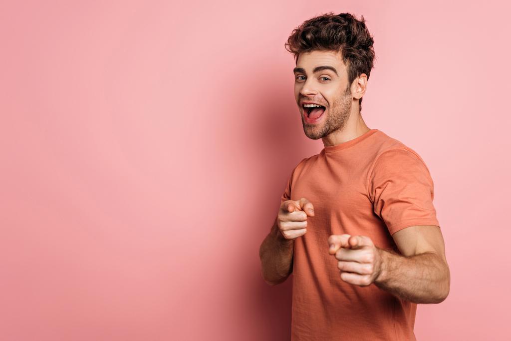 excité jeune homme regardant caméra et pointant avec les doigts sur fond rose
 - Photo, image