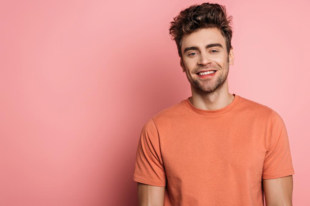 Ευτυχισμένος, όμορφος νεαρός άνδρας χαμογελά στην κάμερα σε ροζ φόντο - Φωτογραφία, εικόνα