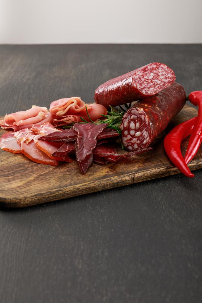おいしい肉の盛り合わせは唐辛子とローズマリーを木製の黒いテーブルの上で - 写真・画像