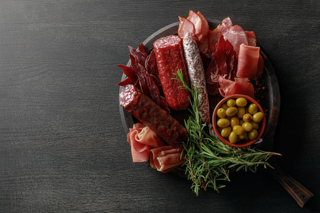 widok z góry pyszne talerz mięsa serwowane z oliwek i ziół na drewnianym czarnym stole - Zdjęcie, obraz