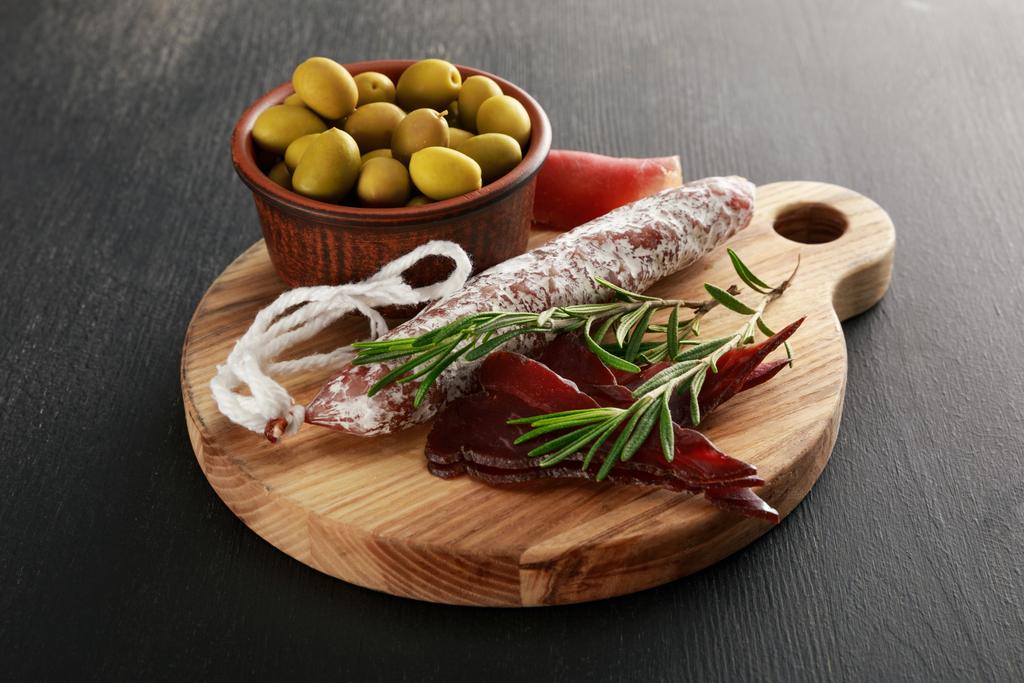 délicieux plateau de viande servi avec des olives à bord sur une surface noire
 - Photo, image