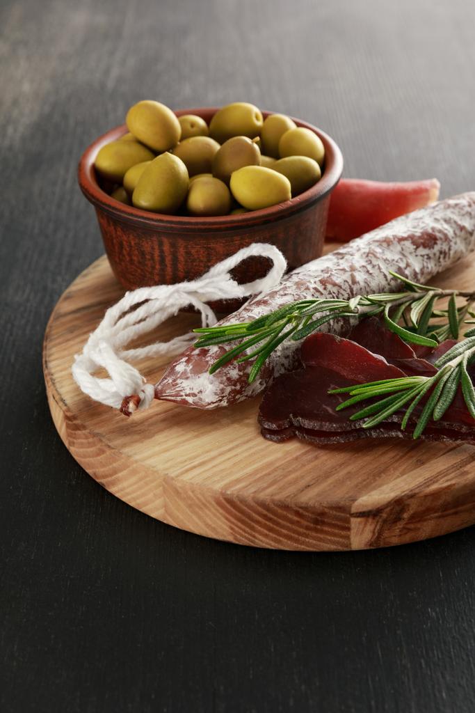 delizioso piatto di carne servito con olive a bordo su superficie nera
 - Foto, immagini