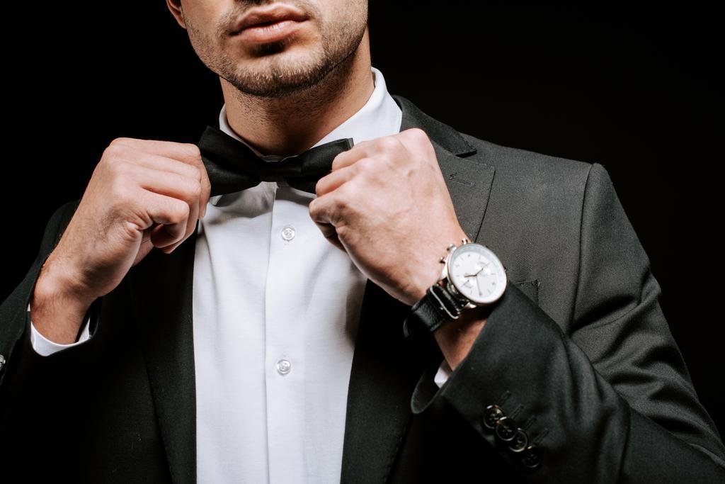 corte vista de homem tocando laço gravata isolada no preto
  - Foto, Imagem