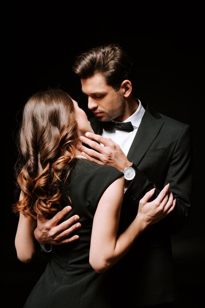 guapo hombre abrazando chica en vestido aislado en negro
  - Foto, imagen