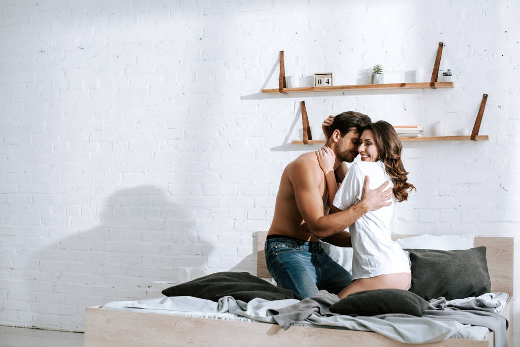 muscular man hugging happy girlfriend in bedroom  - Photo, Image