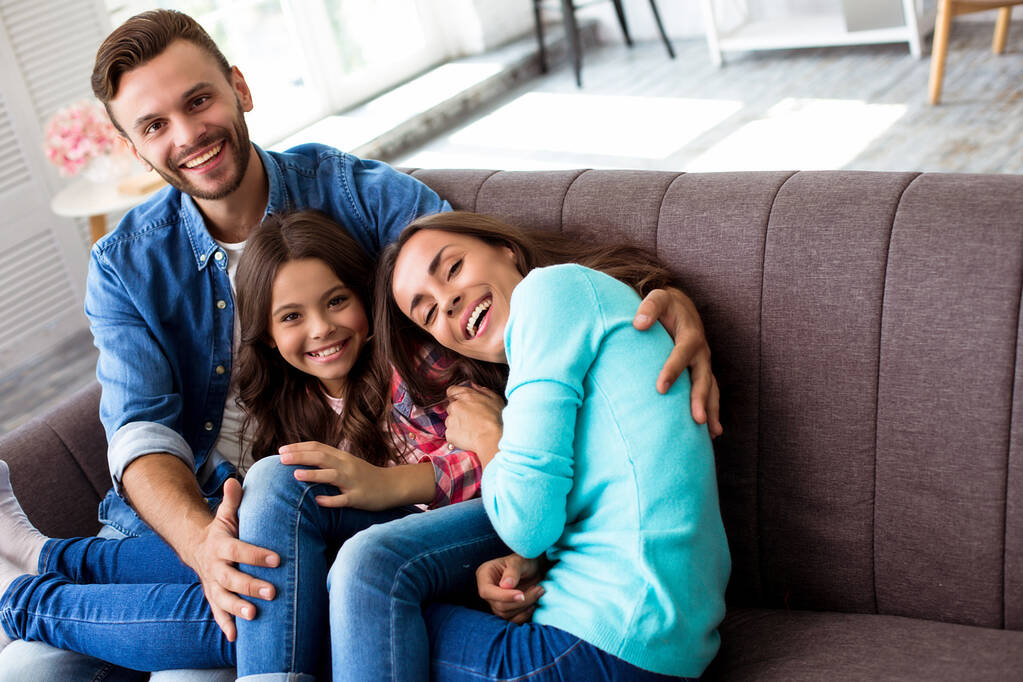 Šťastní mladí rodiče s malou dcerou na pohovce ve svém bytě  - Fotografie, Obrázek