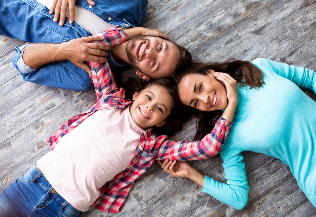 Šťastná mladá trojčlenná rodina ležící na podlaze  - Fotografie, Obrázek
