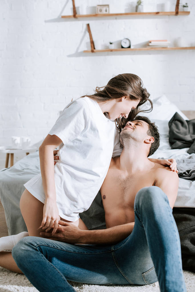 attraente ragazza guardando felice muscolare fidanzato in camera da letto
  - Foto, immagini