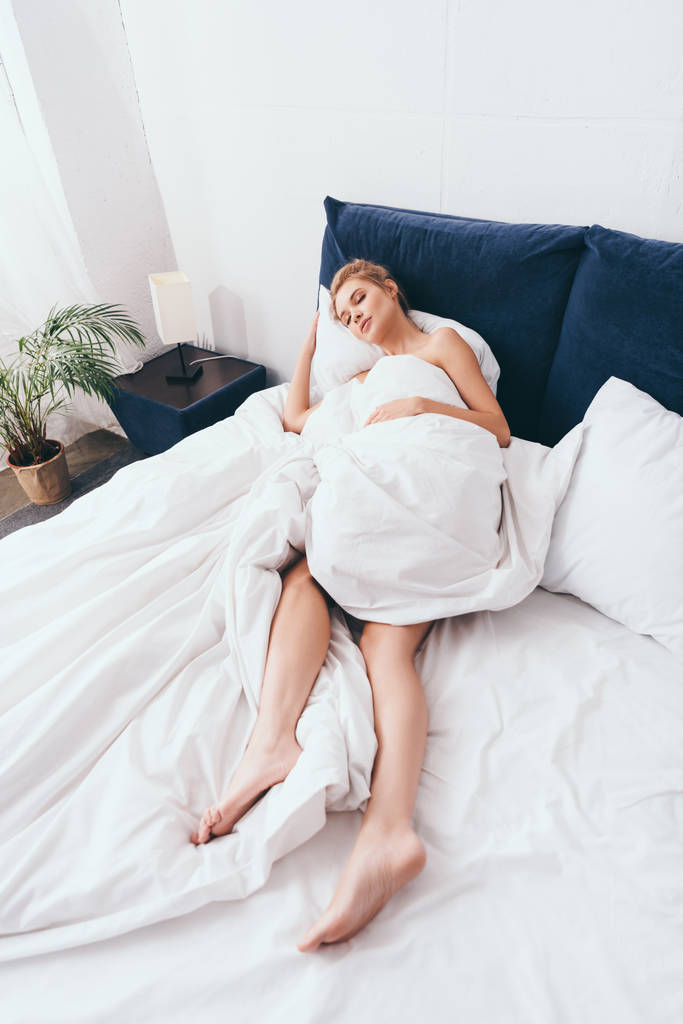 attractive woman sleeping in sheets on bed in morning - Photo, Image
