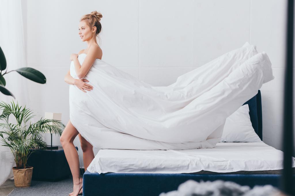 bela mulher sorridente com lençóis brancos no quarto
 - Foto, Imagem