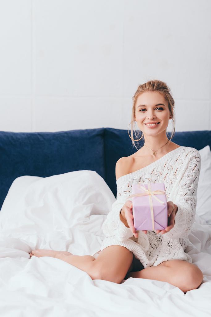 iloinen houkutteleva onnellinen nainen tilalla lahjapaketti sängyllä
 - Valokuva, kuva
