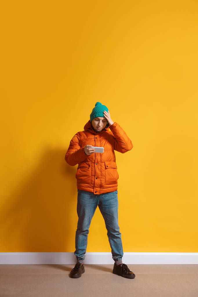 Jeune homme caucasien utilisant un smartphone. Portrait intégral isolé sur fond jaune
. - Photo, image